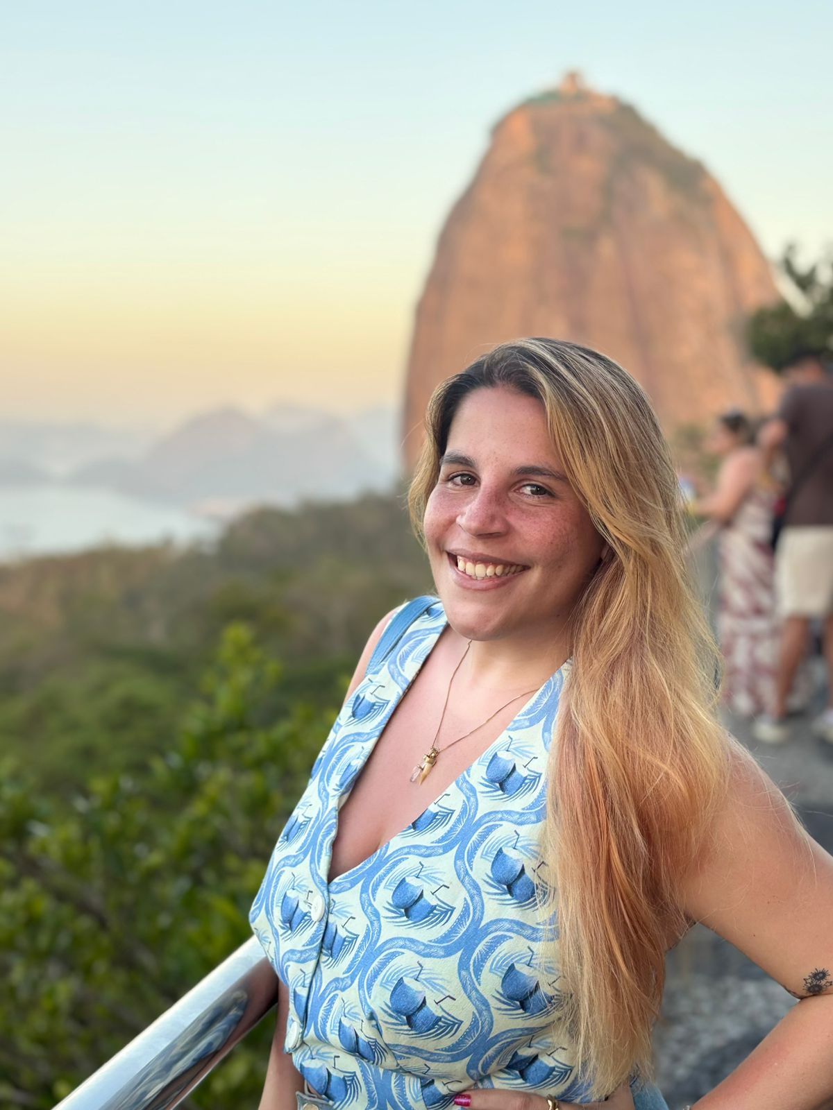 Mulher fotografada ao pôr do sol, com o Pão de Açúcar por trás
